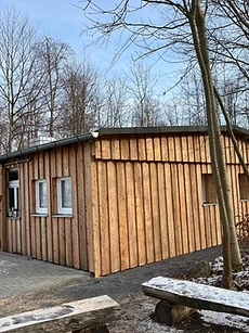 Holzhütte aus senkrechten Fichtenbrettern mit geschnitztem Baummotiv an der Fassade