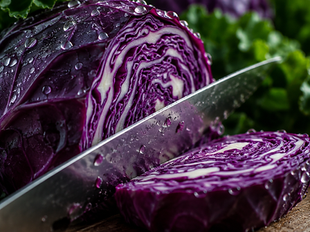 Macro close-up of a knife slicing through a vibrant purple cabbage