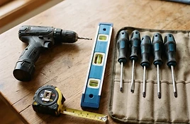 Top-down photo of a tidy home toolkit with a drill, spirit level and measuring tape
