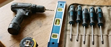 Top-down photo of a tidy home toolkit with a drill, spirit level and measuring tape