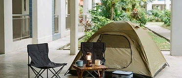 Tent, folding camping chairs and a lantern set up at an HDB void deck