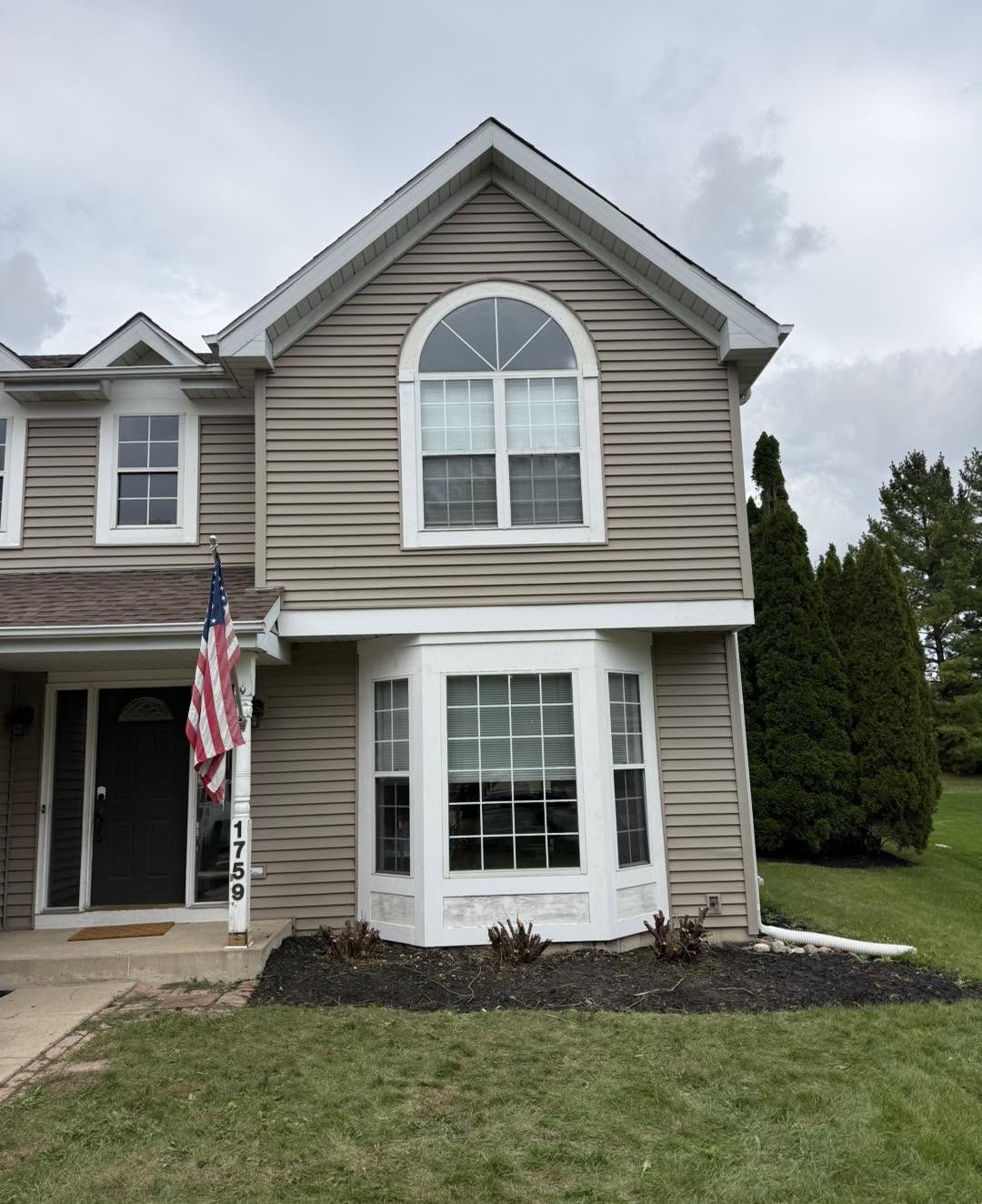 Home exterior with arched window and bay window by Fisher Remodeling