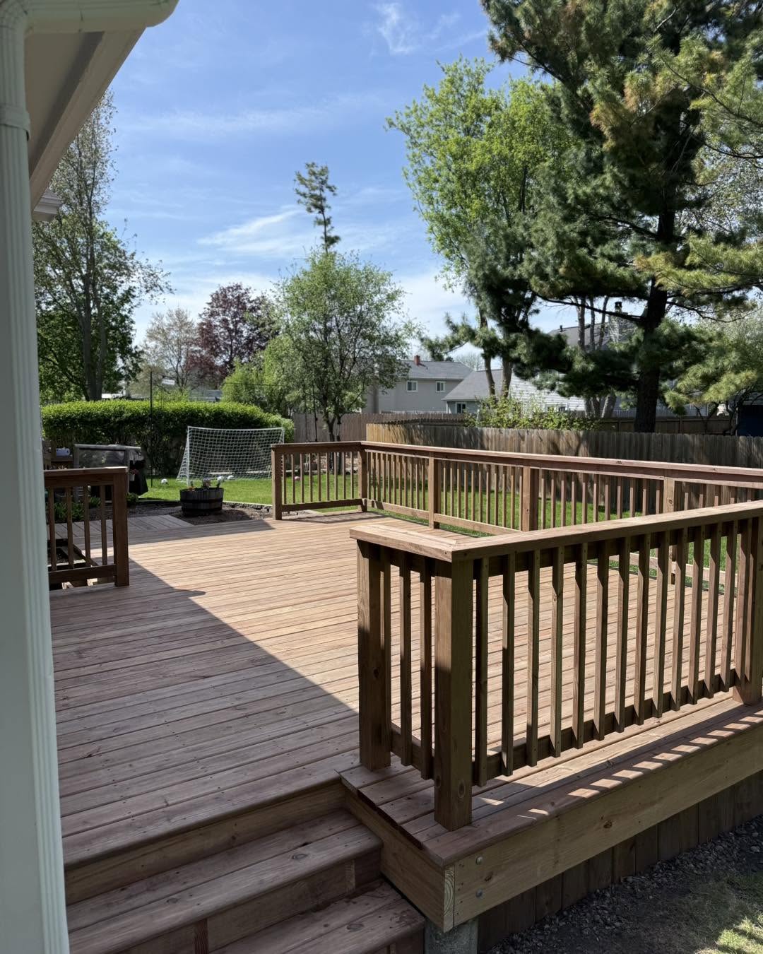 Backyard deck with railings and wide steps by Fisher Remodeling