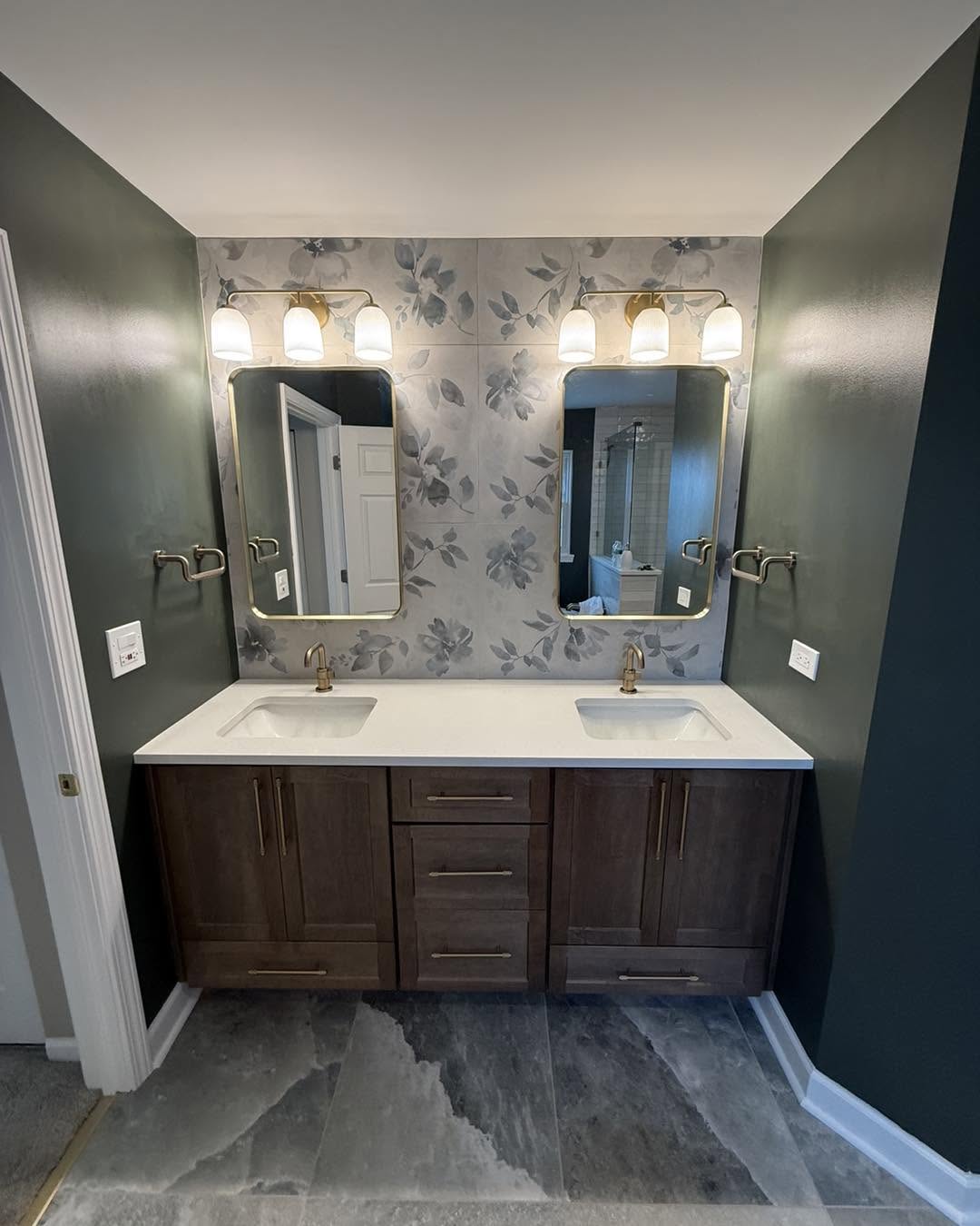 Primary bath double vanity with dark wood cabinetry, floral accent tile and brass fixtures by Fisher Remodeling