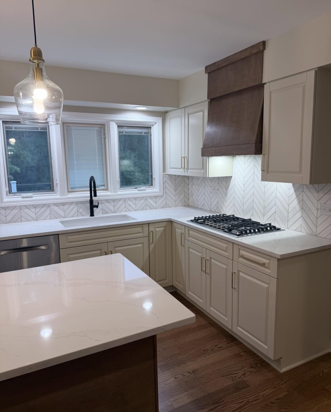 Kitchen remodel with custom range hood, marble island and pendant light by Fisher Remodeling