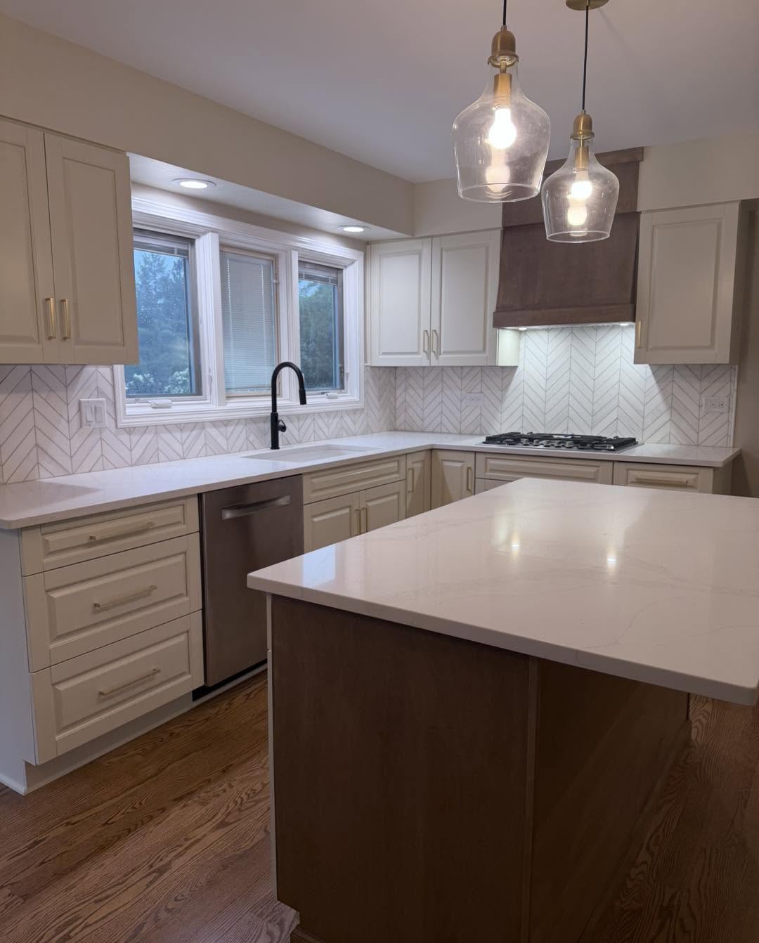 Cream kitchen island with marble countertop and glass pendant lights by Fisher Remodeling