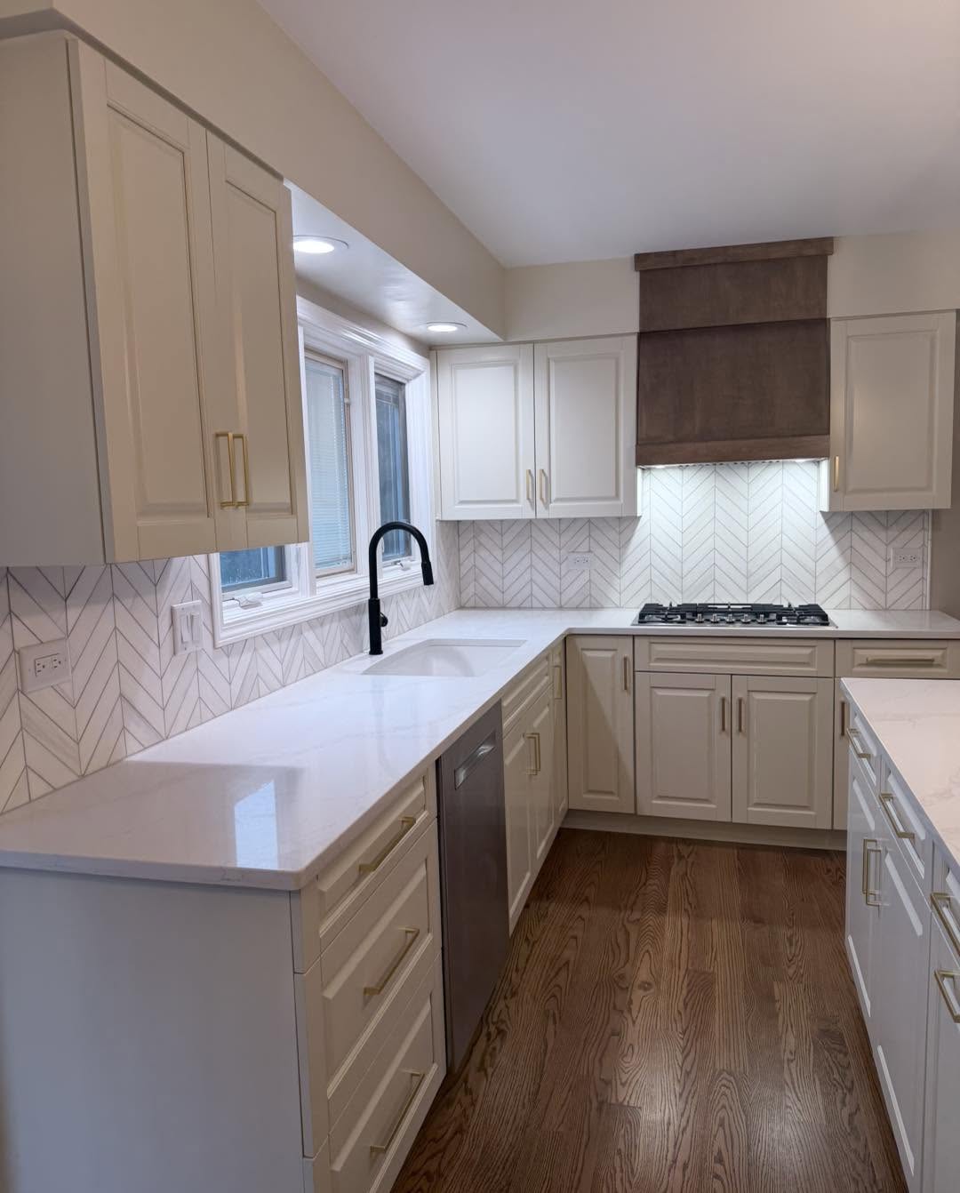 Cream kitchen with herringbone marble backsplash and oak floors by Fisher Remodeling