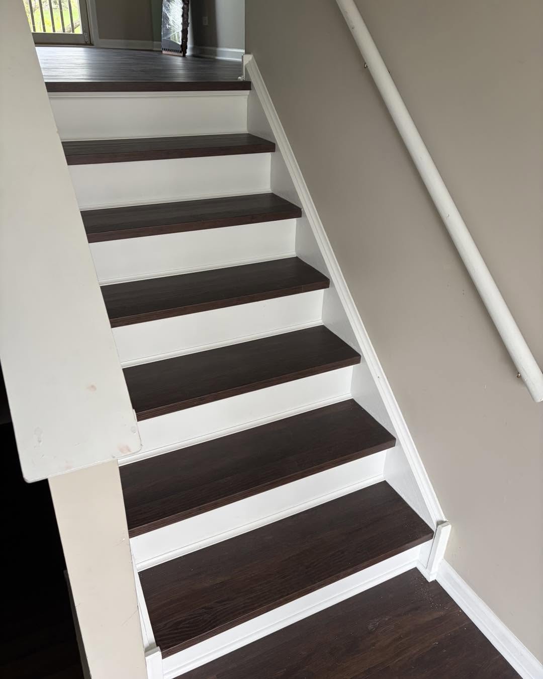 Staircase with dark wood treads and white risers by Fisher Remodeling