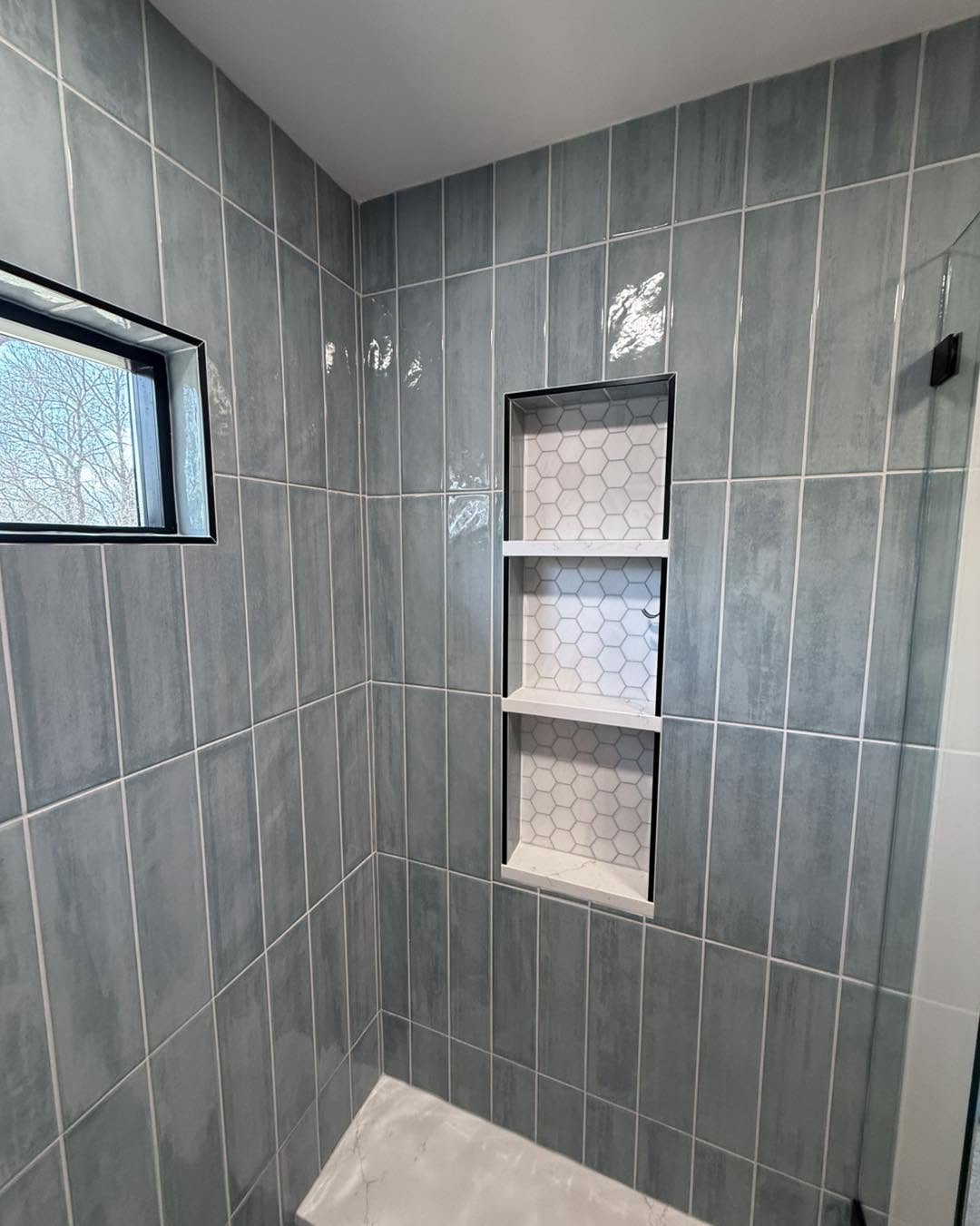 Grey-blue tiled shower with built-in hexagon tile niche by Fisher Remodeling