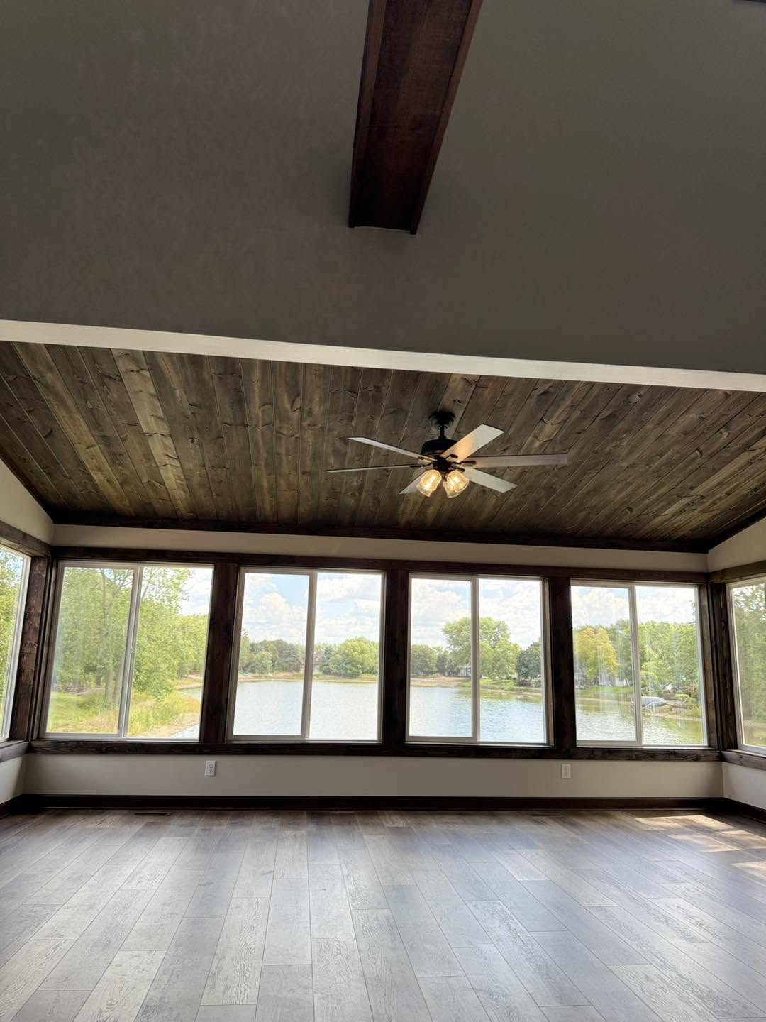 Rustic wood plank ceiling with casement windows overlooking a lake by Fisher Remodeling