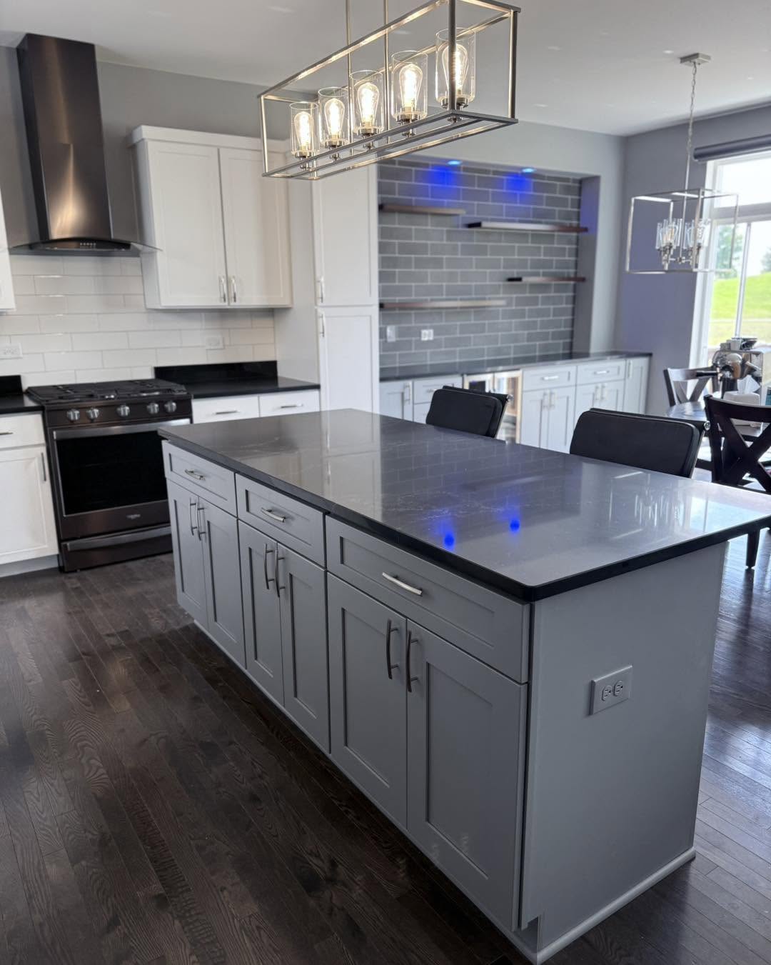Grey kitchen island with black countertop and pendant lighting by Fisher Remodeling