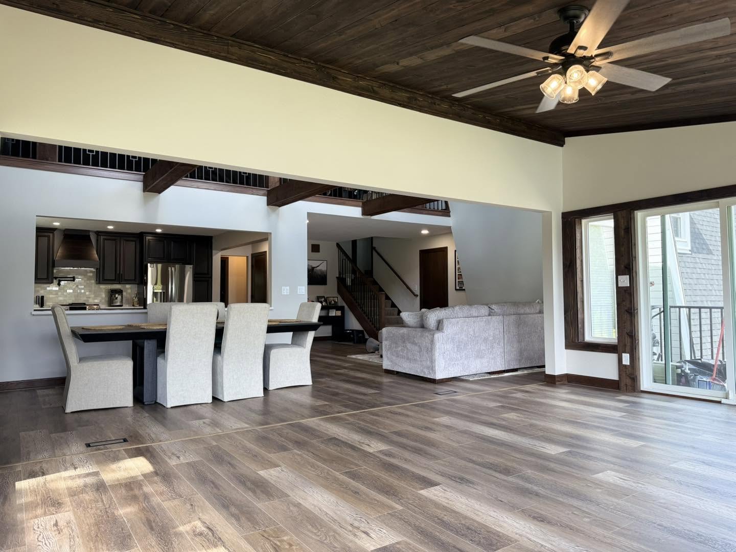 Open-concept living, dining and kitchen with exposed timber beams by Fisher Remodeling