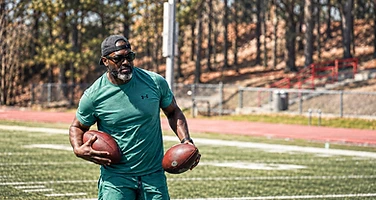 Athlete holding footballs on the field