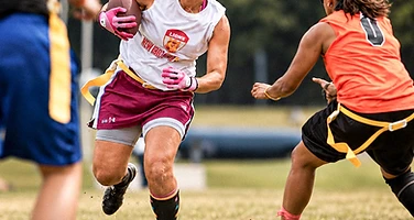 Female flag football player running with ball