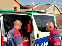 Two Guardian EMS paramedics preparing equipment at an open ambulance