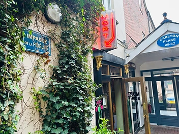 Entrance to Mort Subite bar with red neon sign and ivy-covered wall