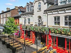 Exterior of Kennedy's Irish Bar in Altrincham with red facade, hanging baskets and outdoor seating