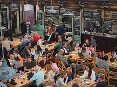 Busy Market House interior with communal dining tables and independent food stalls including Honest Crust pizza.