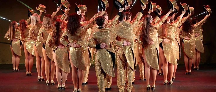 Altrincham Garrick Playhouse performers in gold tailcoat costumes during a stage production