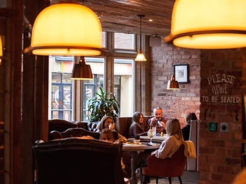 Interior of Toast Altrincham restaurant, with diners seated at a table and warm pendant lighting