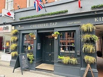 Exterior of Cheshire Tap freehouse in Altrincham, with hanging baskets and chalkboard sign