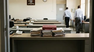 A series of empty desks arranged in a provincial government office in Ndola are topped with official documents detailing security operations and administrative logs.
