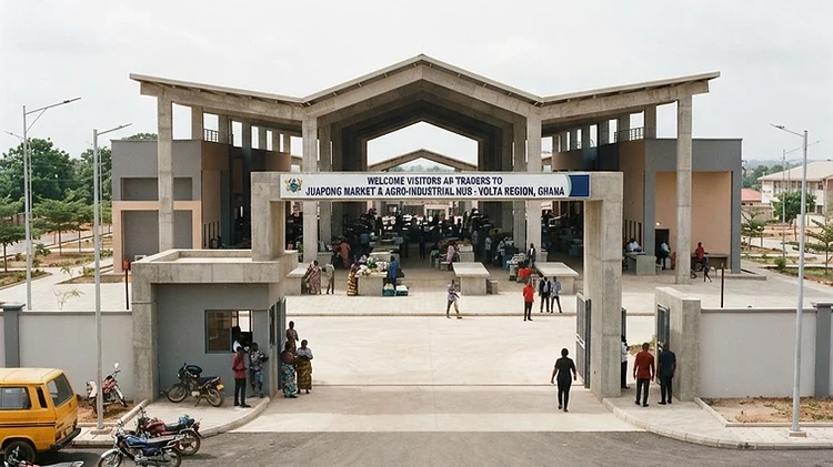 The main entrance and concrete architecture of the Juapong industrial market facility featuring official state development signage in the Volta Region of Ghana.