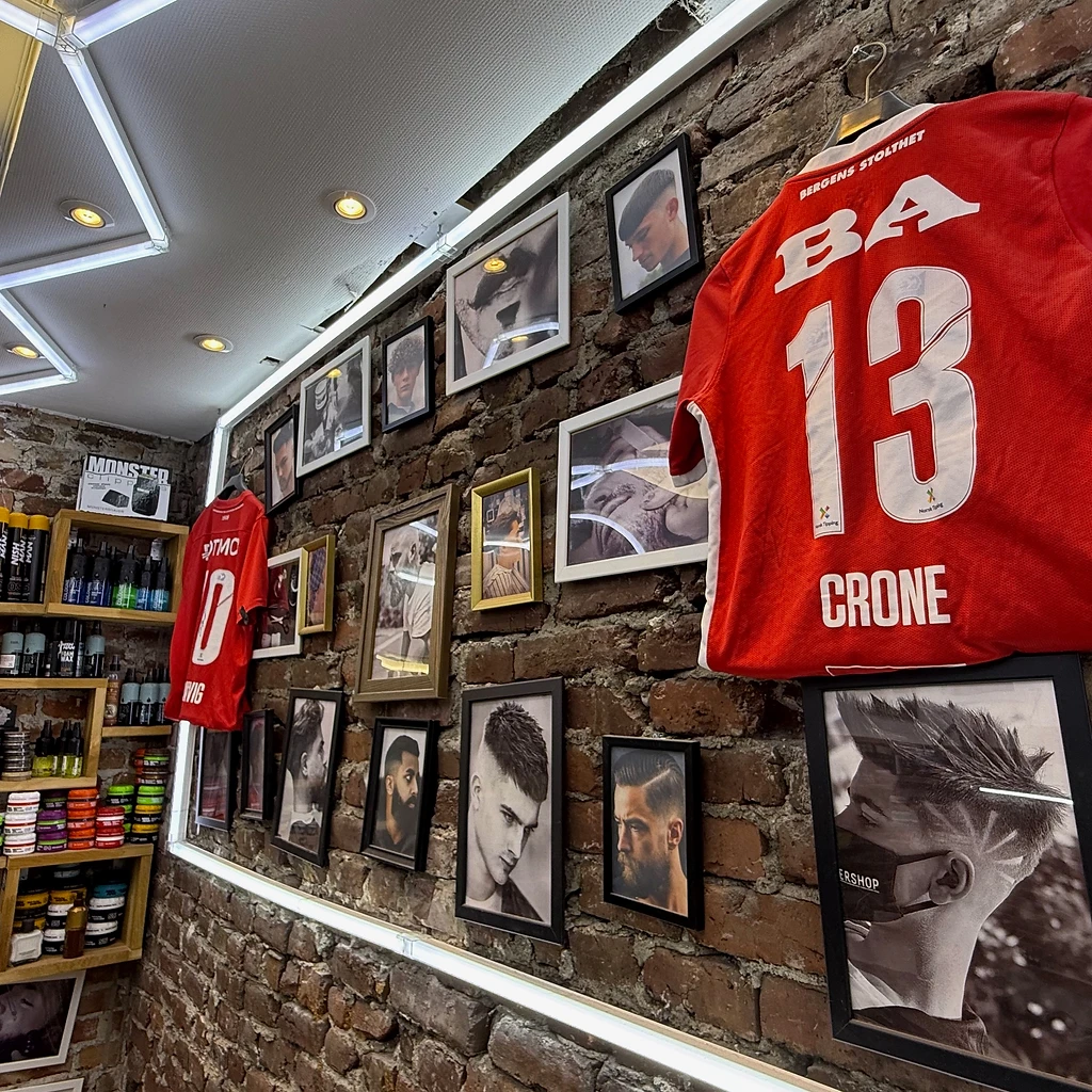 Framed barber photographs and football shirts on the brick wall