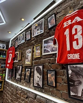 Framed barber photographs and football shirts on the brick wall