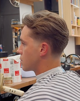 Slicked-back men’s haircut with a soft blend at the sides