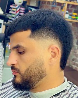 Short dark hair with a fade and shaped beard, viewed from the side