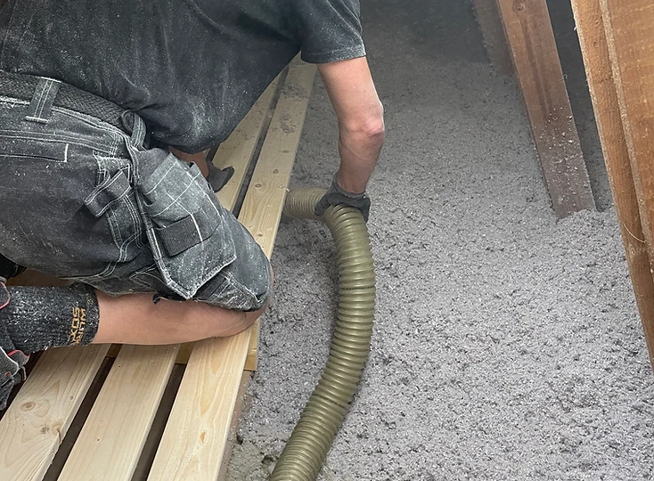 Jeppe fra Sand Isolering arbejder med indblæsningsslangen på et loft