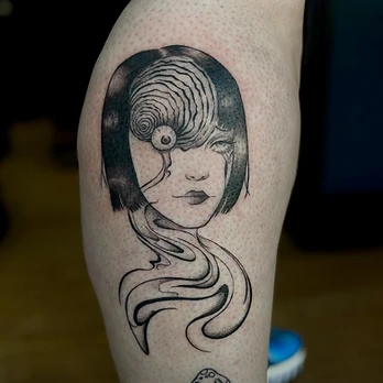 Fine-line black and grey tattoo portrait of a woman with a short bob, a spiral containing a single eye worked into the side of her head, on a thigh