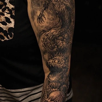Dark black and grey gothic fantasy tattoo of a skeletal female figure above a horned creature with tentacles on an outer arm