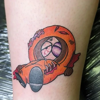 Colour cartoon tattoo of Kenny from South Park in his orange parka, lying on his side with a bruised eye, bloodshot eyes and ribs showing through a tear in the hood