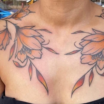 Symmetrical traditional colour tattoo of two mirrored floral arrangements in burnt orange, peach and yellow shading across the collarbones and chest
