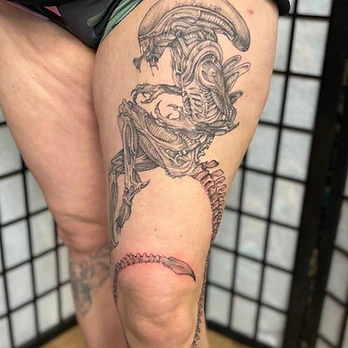Fine-line black and grey tattoo of an Alien xenomorph in profile, its segmented tail curving down the leg, on a thigh