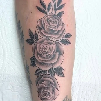 Fine-line black and grey tattoo of three roses stacked vertically with leaves between them and fine dotwork at the tips