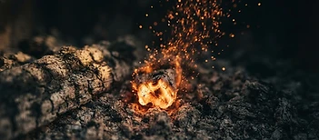 A single glowing ember rising from dark ash