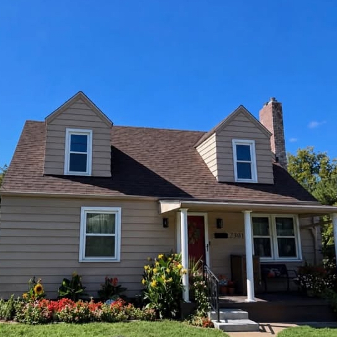 Finished brown roof on a tan two story home with dormers