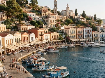 Ochre and white houses with arcades along the waterfront of Poros Town, with a clock tower above.