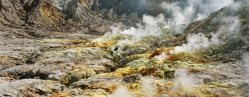 The floor of the Stefanos crater on Nisyros: pale grey ash, yellow sulphur crusts and steam venting from cracks.