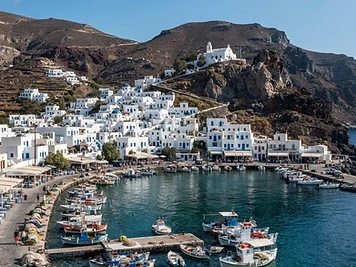 White houses in a ring around the bay at Mandraki on Nisyros, with the monastery on the rock above.
