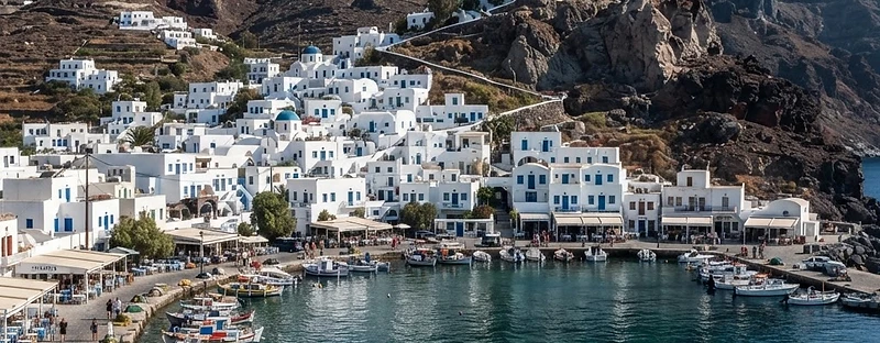 White houses in a ring around the bay at Mandraki on Nisyros, with the monastery on the rock above.