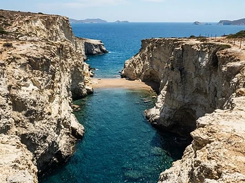 A narrow slot of pale rock opening to deep blue water at Papafragas on Milos.