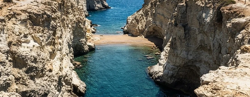 A narrow slot of pale rock opening to deep blue water at Papafragas on Milos.