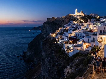 Whitewashed houses of Chora on Folegandros along the edge of the cliff at dusk.
