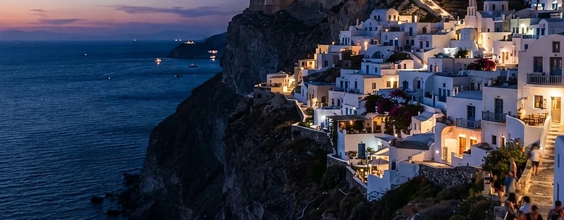 Whitewashed houses of Chora on Folegandros along the edge of the cliff at dusk.