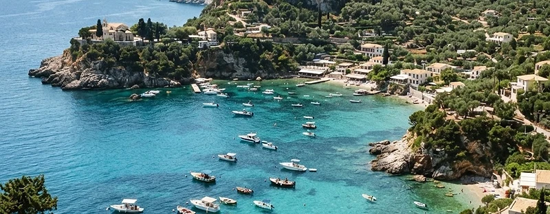 A horseshoe of turquoise water below wooded cliffs at Paleokastritsa, Corfu.