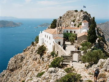 A whitewashed monastery on a rocky ridge above the sea on Hydra.